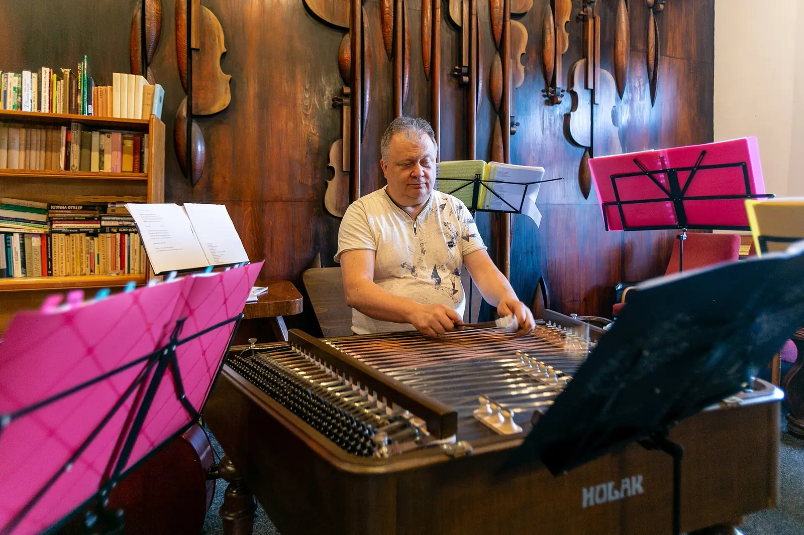 A musician playing a cimbalom, the hammered dulcimer of Moravian folk bands, at a concert in Ostrava, with violin music stands beside him