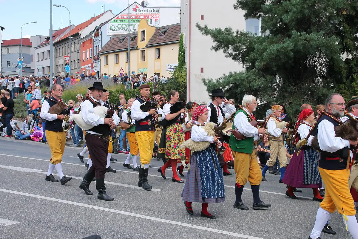 Bagpipers in regional costume marching in a street parade, with colourful skirts and yellow trousers, in a Czech town